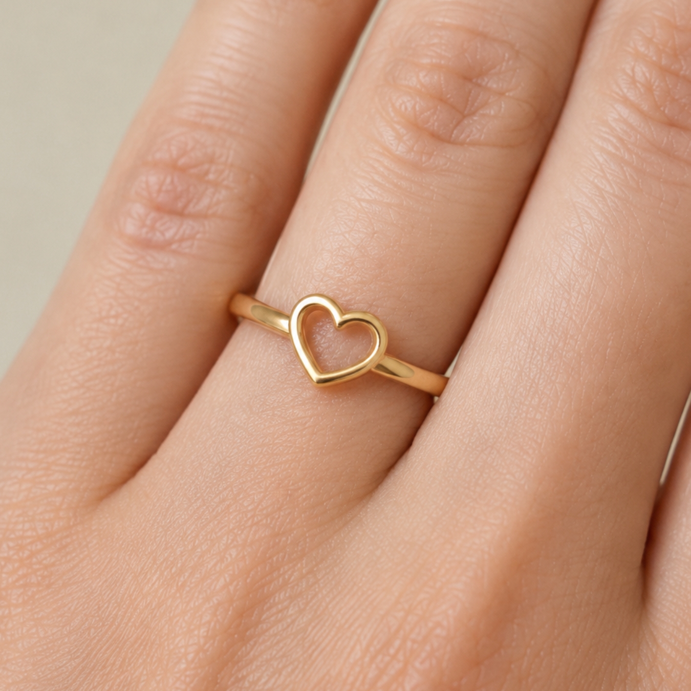 Anel de coração em ouro 18k minimalista em detalhe no dedo de uma pessoa.